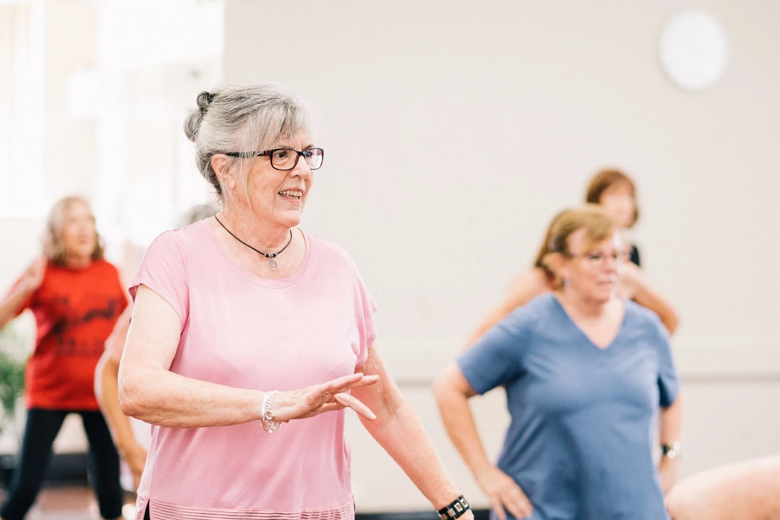 Mutuelle Sante Senior : Senior women participating in a lively and joyful group exercise session indoors.
