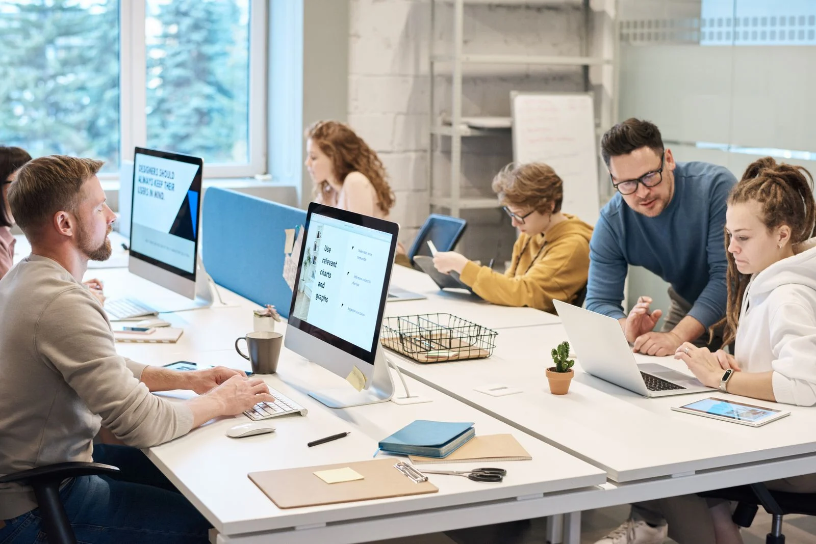 Mutuelle Entreprise Collective : Team collaboration in a modern office setting with computers and diverse employees working together.