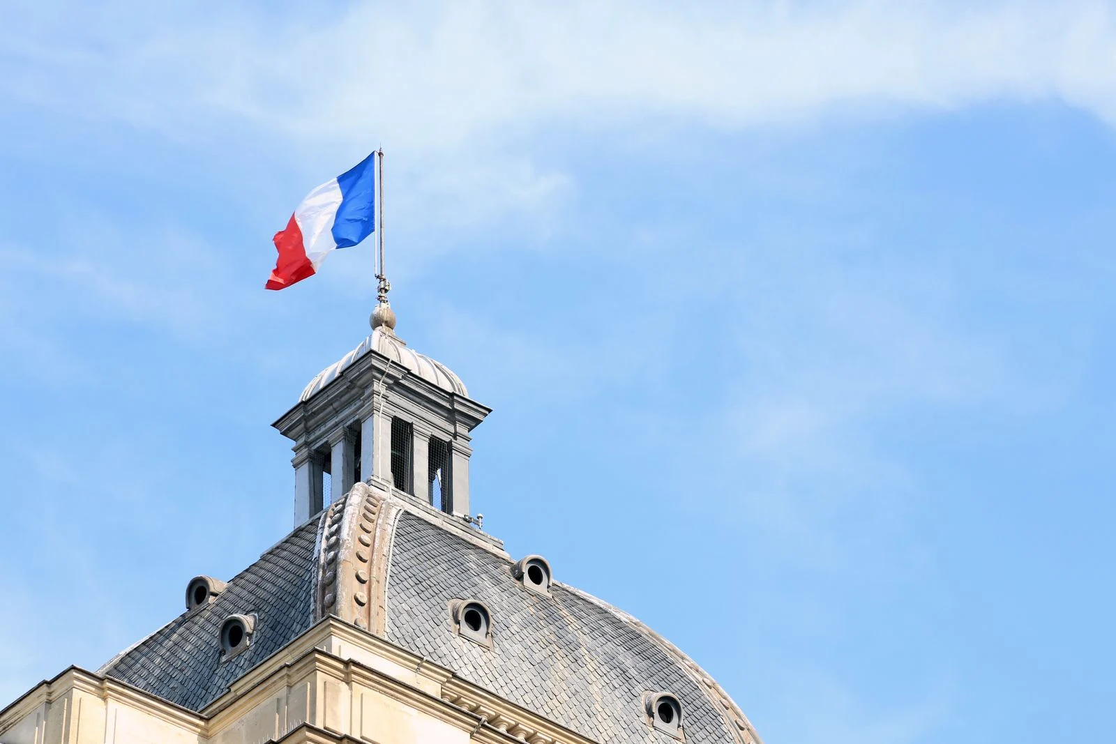 Mutuelle senior : The French flag waves atop the dome of historic architecture in Paris, France.