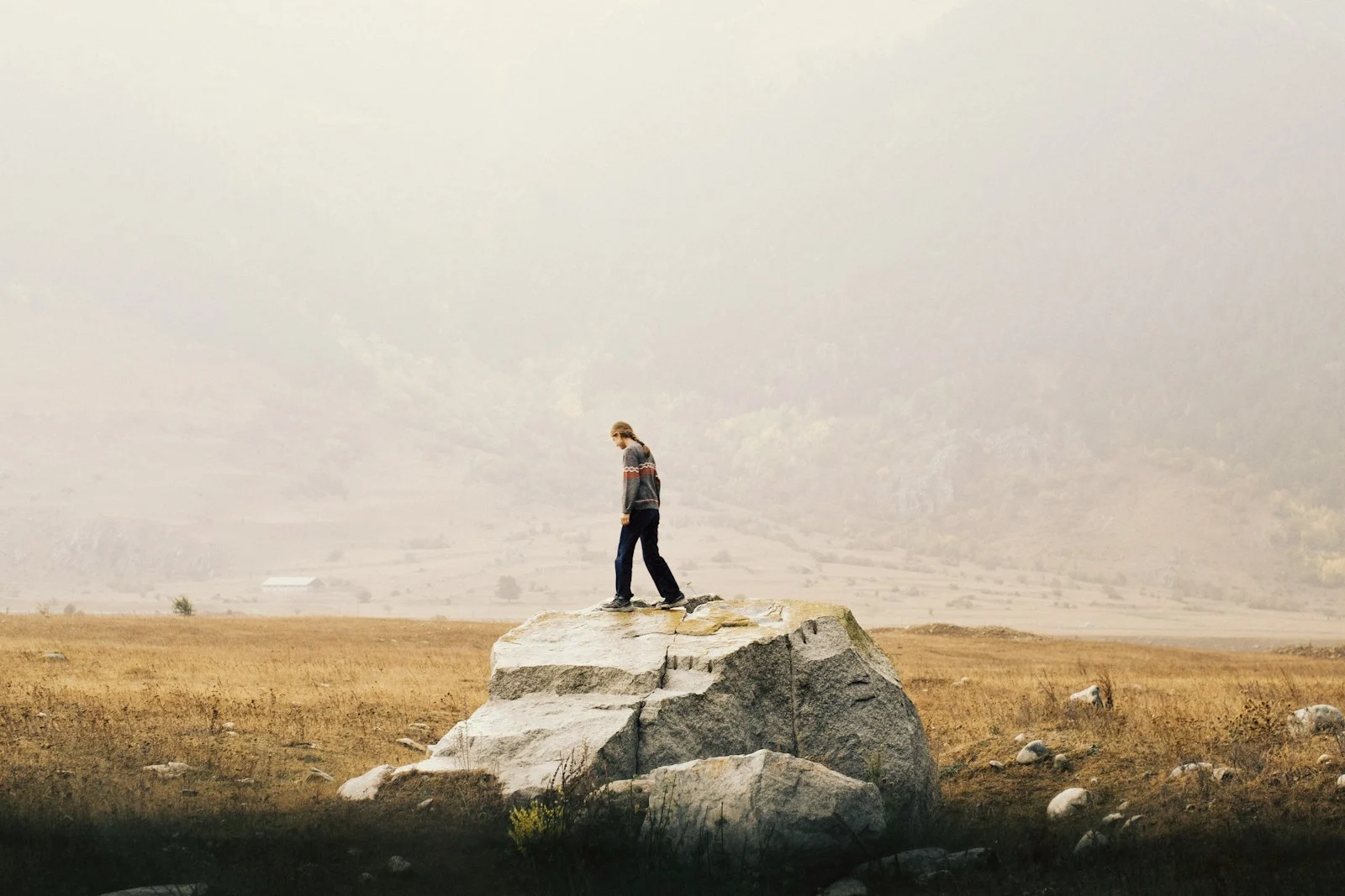 Expatrie : A person in a patterned sweater walking on a large boulder in Teberda, Russia