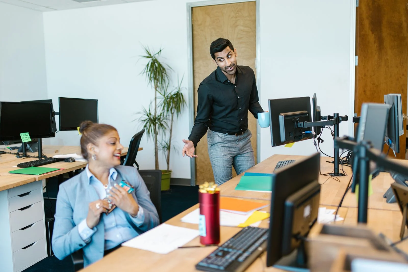 Mutuelle Entreprise Collective : Two colleagues engaging in a cheerful conversation in a modern office setting.
