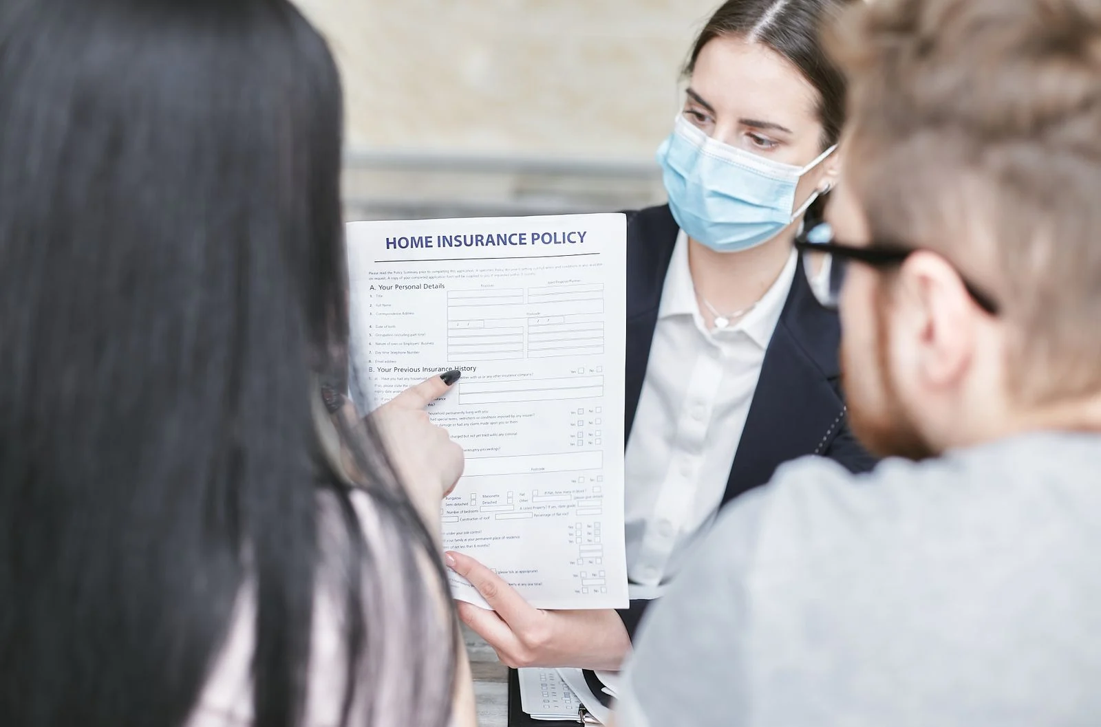 mutuelle santé :A professional woman explains a home insurance policy to clients during a meeting. Indoors setting.