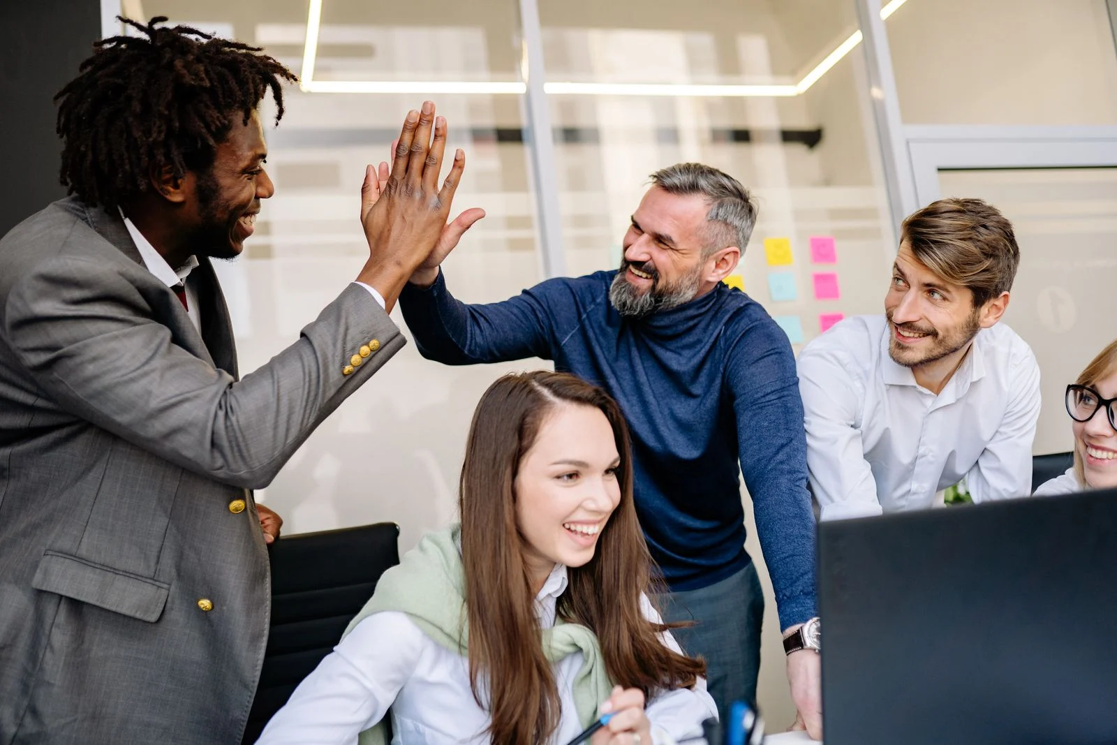 Mutuelle Entreprise Collective : A diverse team happily celebrates a workplace achievement with high-fives.
