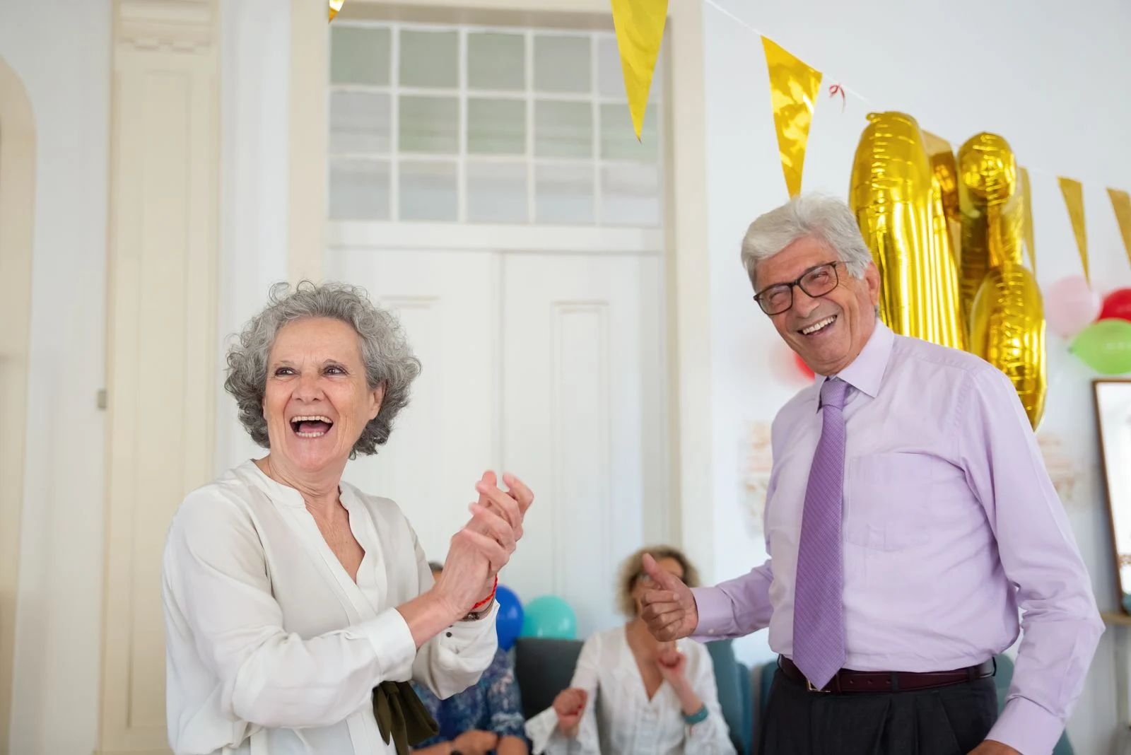 Mutuelle Sante Senior : Happy seniors celebrating indoors with balloons and laughter. Perfect for festive and joyful lifestyle themes.