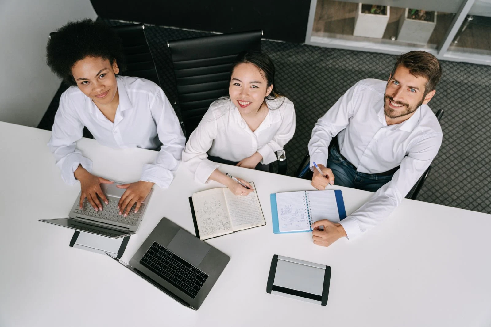 Mutuelle Entreprise Collective : A diverse group of professionals collaborating during an office meeting, using laptops and notebooks.