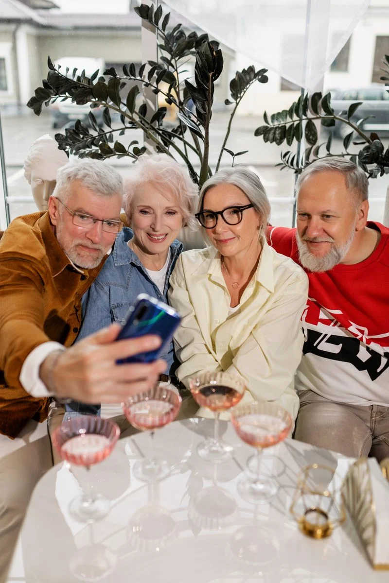 Mutuelle Sante Senior : Senior friends share a joyful moment taking a selfie together, indoors.