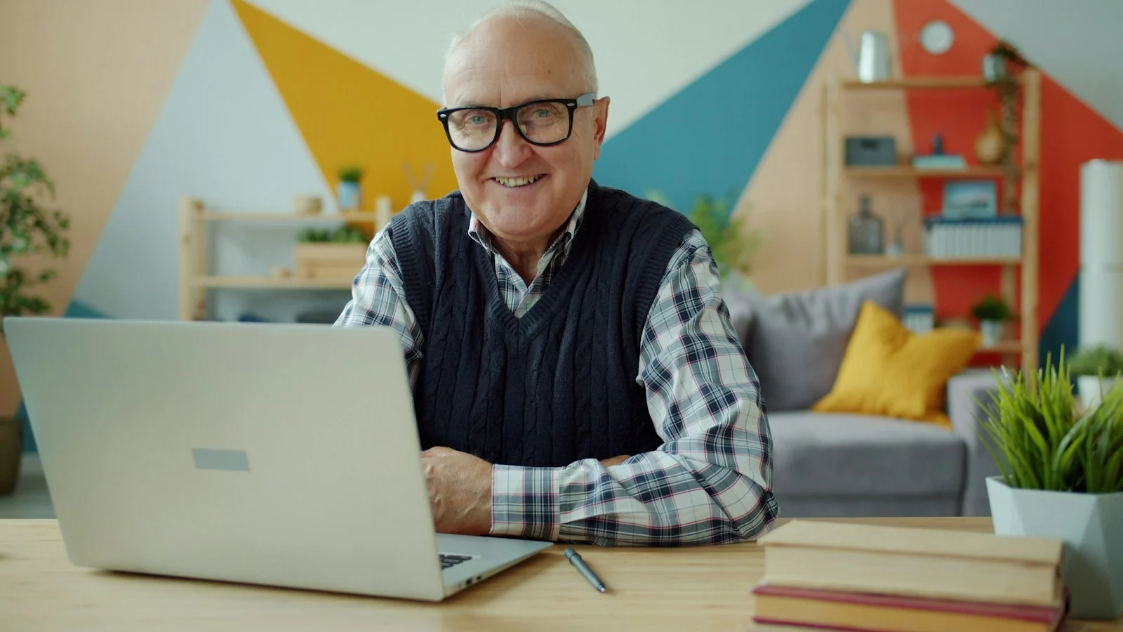 Comparatif Mutuelle senior Smiling elderly man with glasses at laptop computer