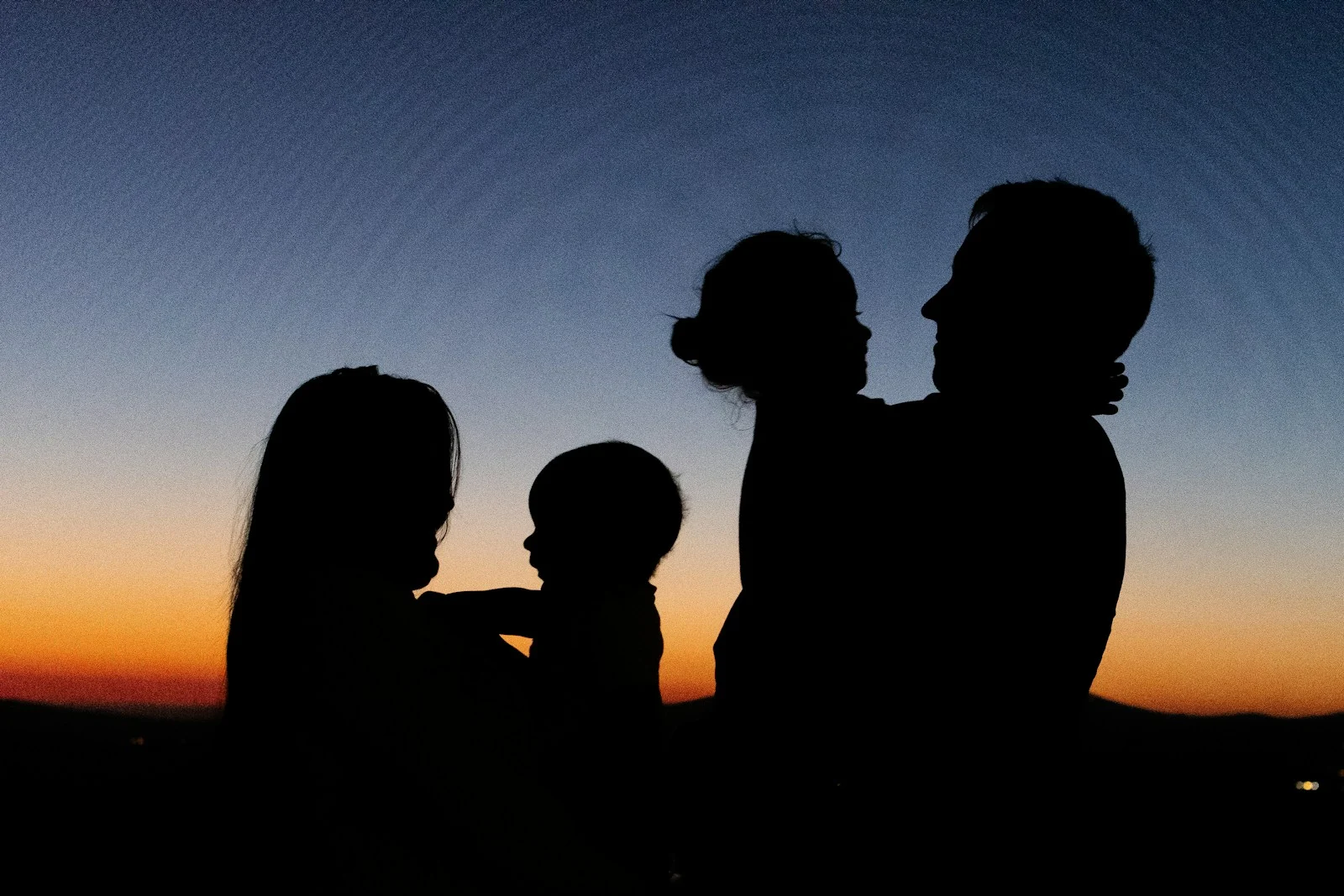 Family silhouette of 2 women and man standing during sunset