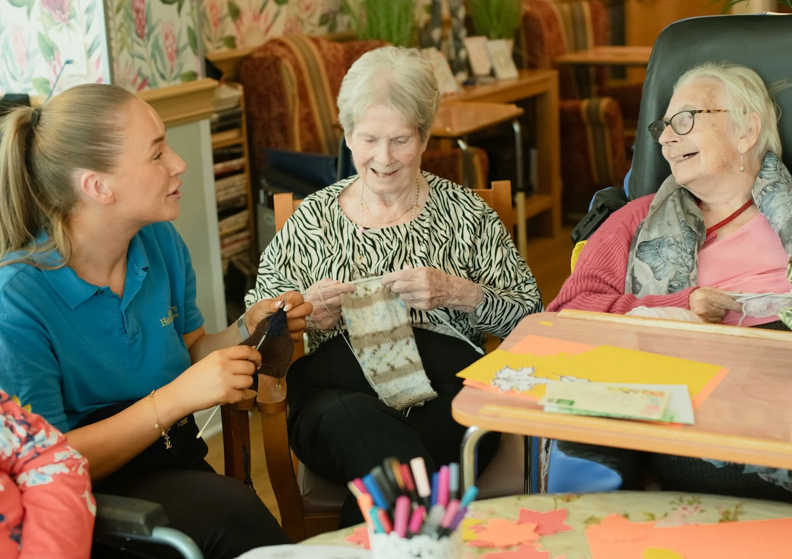 Mutuelle Sante Senior : Caregiver assists two elderly women knitting