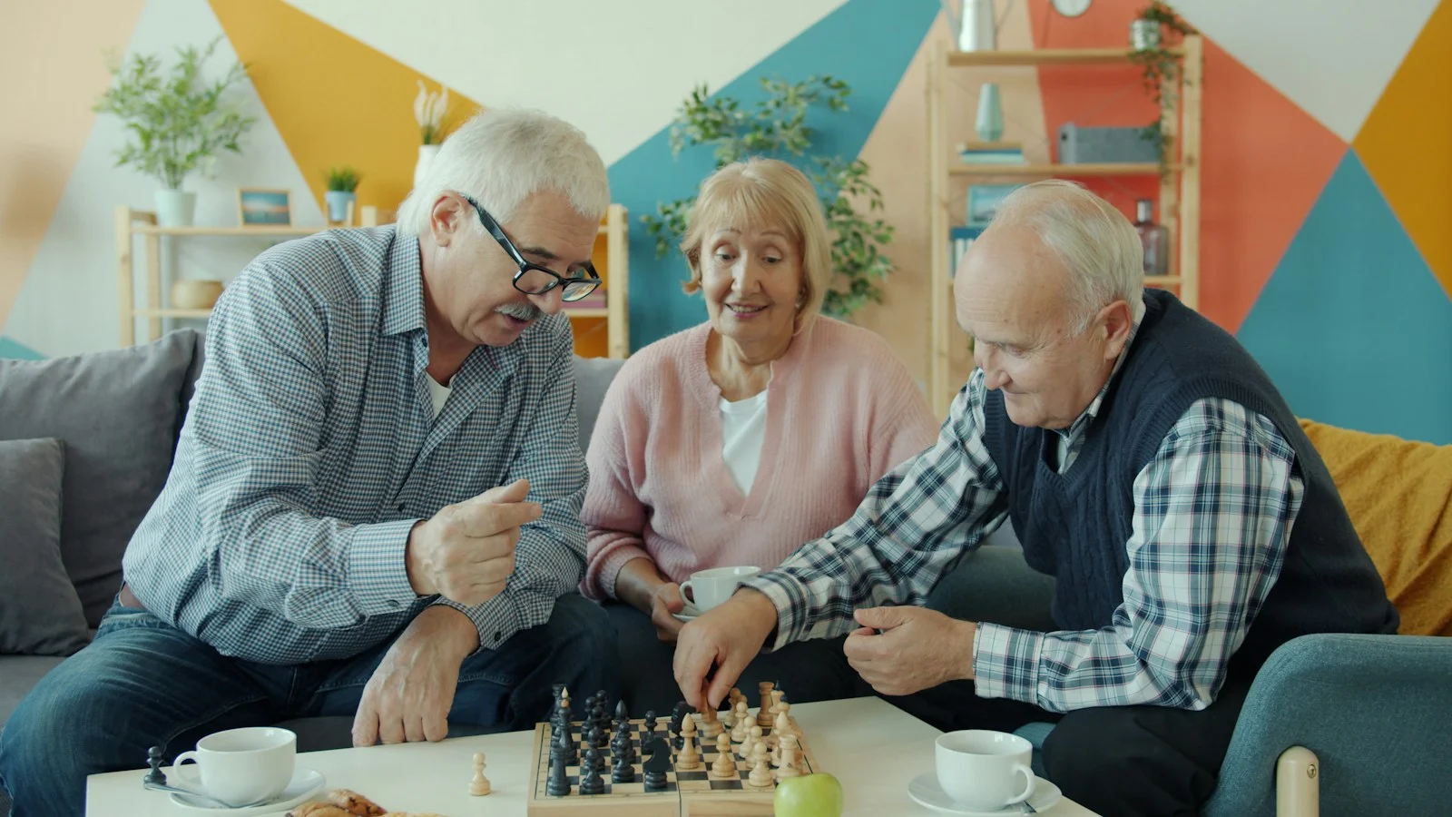 Mutuelle Sante Senior : Three seniors playing chess together in a living room