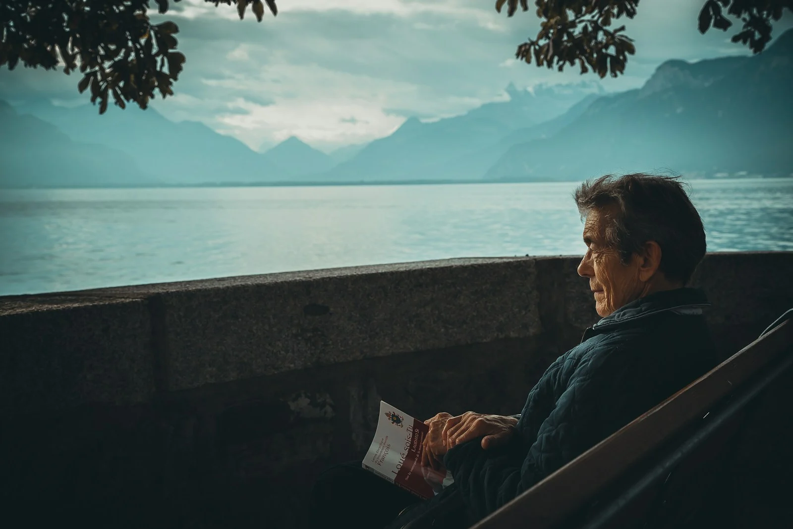 Mutuelle Sante Senior : man sitting while holding a book watching on body of water