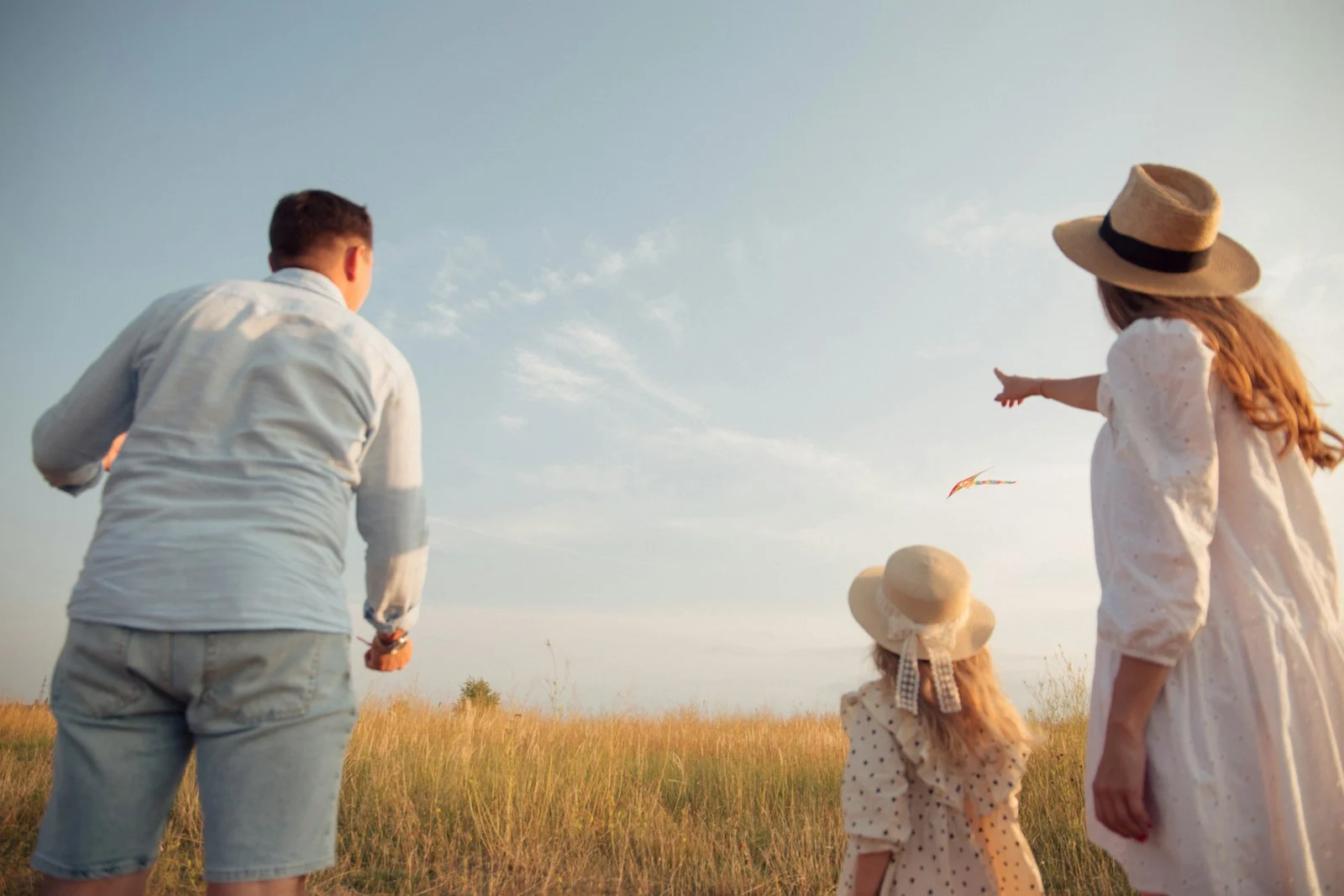 family in a field flying a kite under a clear blue sky