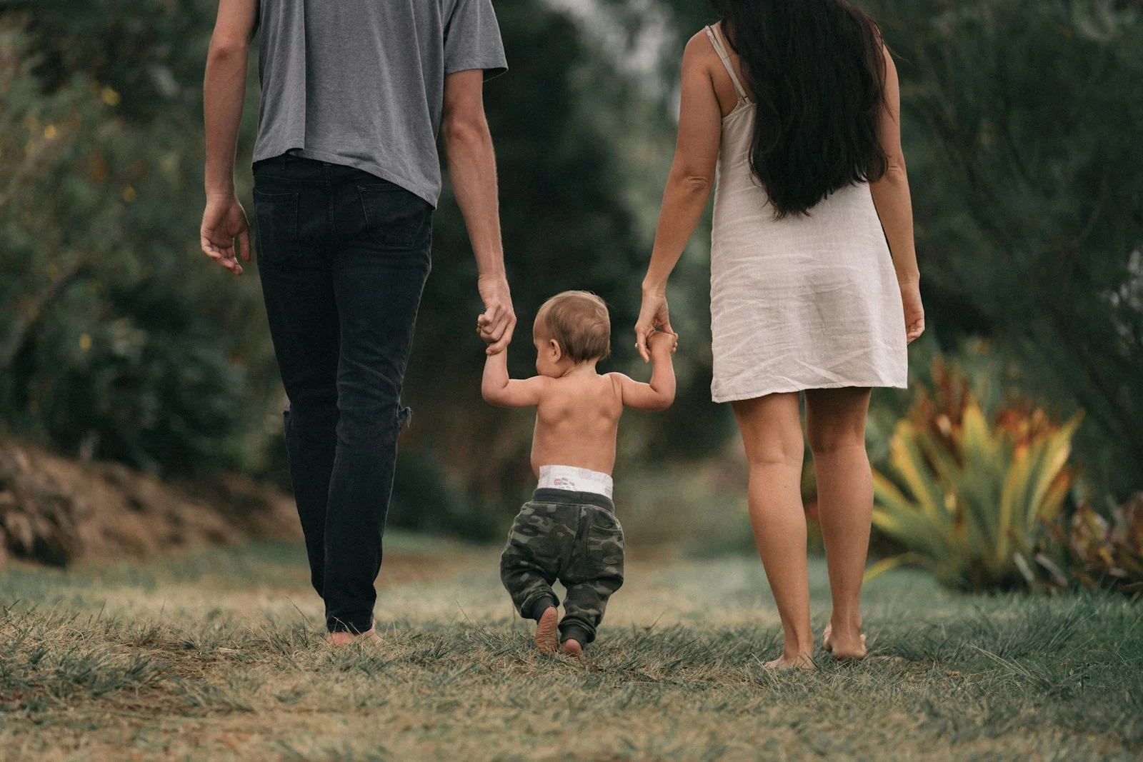 Family couple walking barefoot with a child at the garden