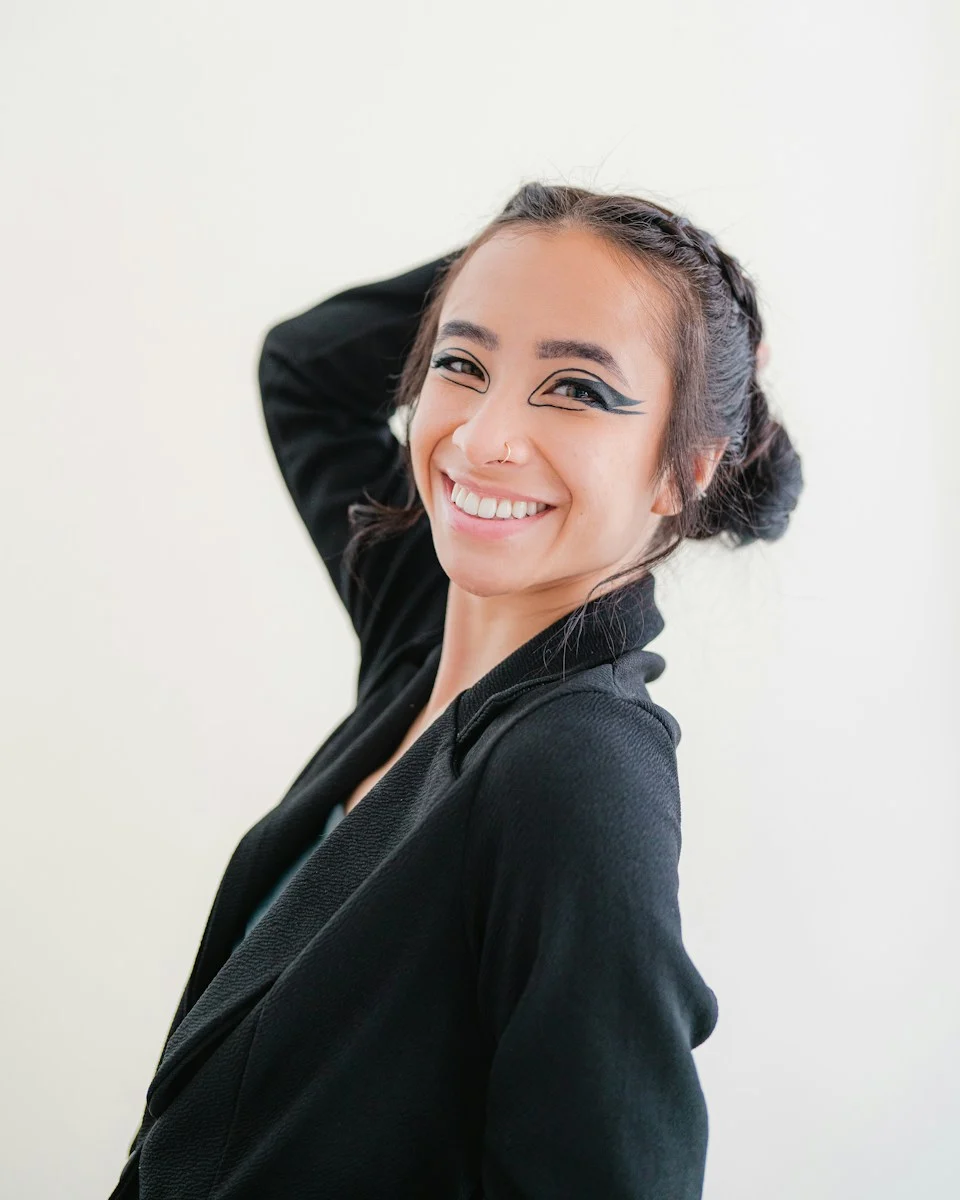 Mutuelle Individuelle : a smiling woman in a black jacket with her hair in a bun