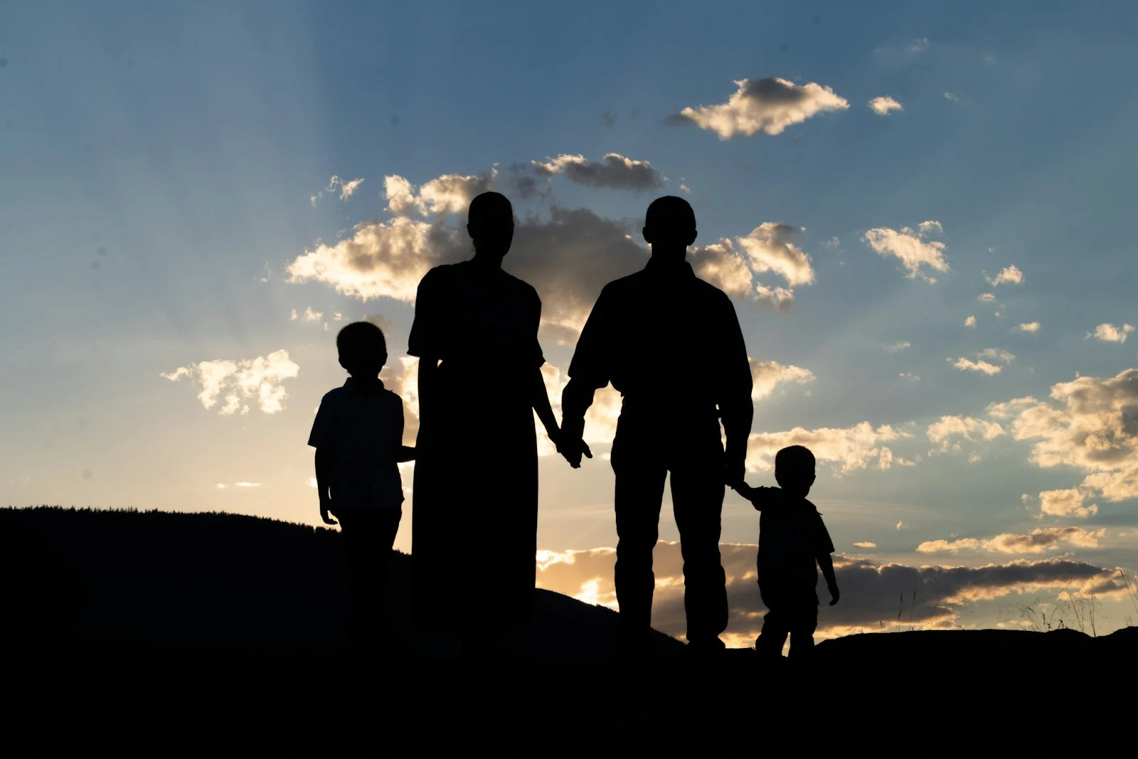 Family a group of people standing on a hill looking at the sunset