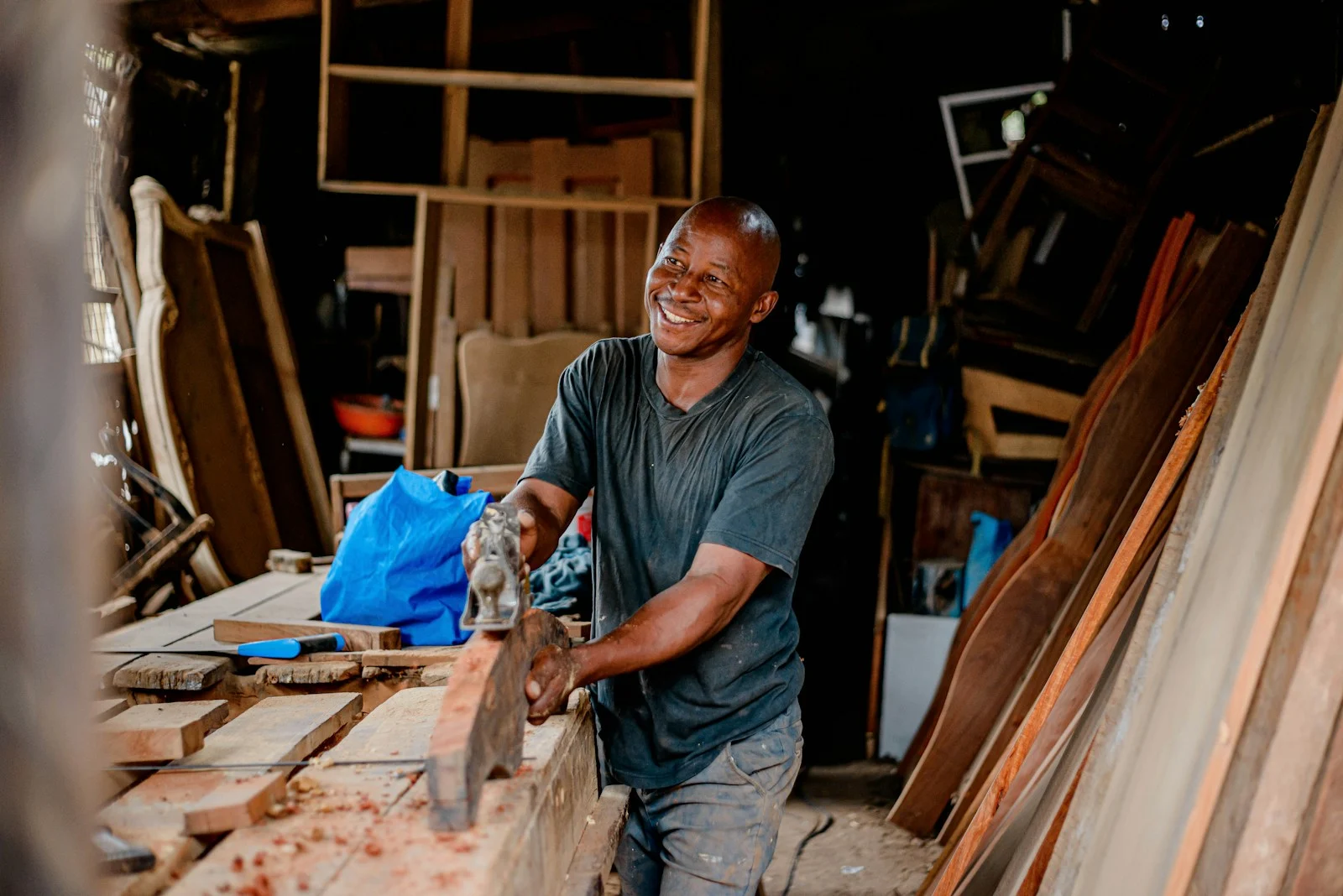 TNS : a man smiles as he works on a piece of wood