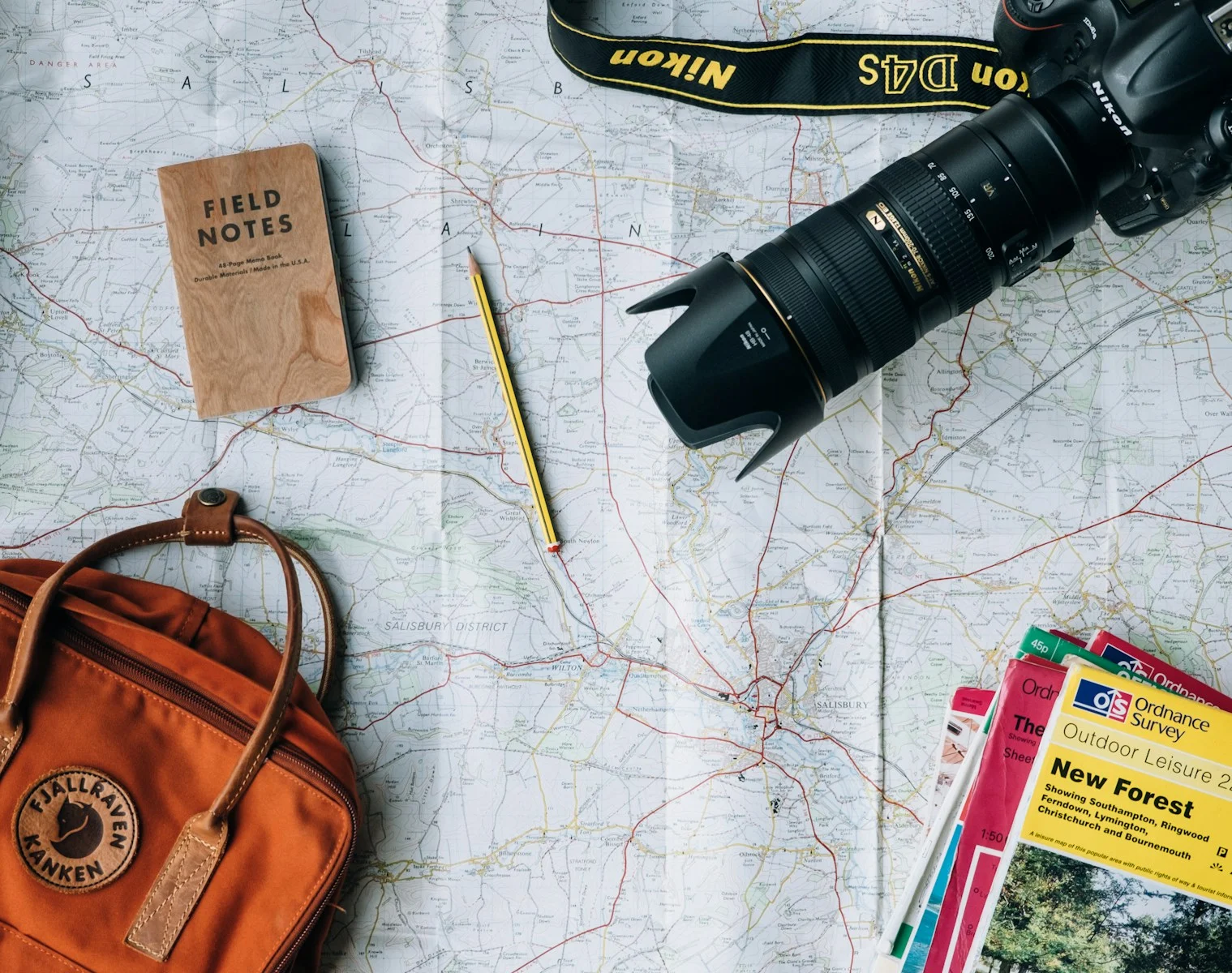 Expatrie : flat lay photography of camera, book, and bag