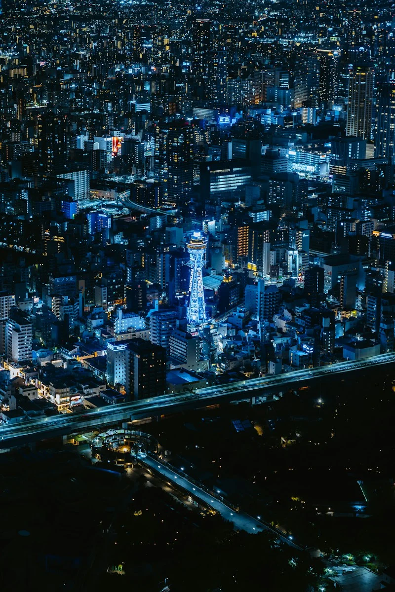 Vue aérienne nocturne de la tour Tsutenkaku illuminée à Osaka, illustration pour complément CFE remboursement