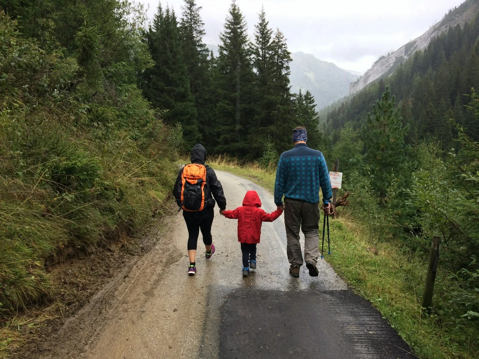 Family man, woman, and child walking together along dirt road
