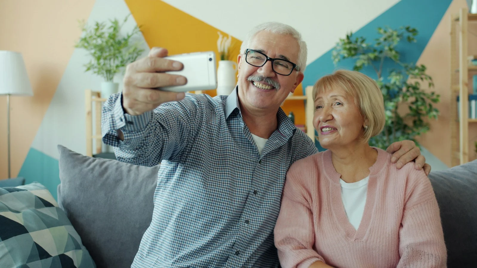 Mutuelle Sante Senior : Elderly couple taking a selfie together on the couch