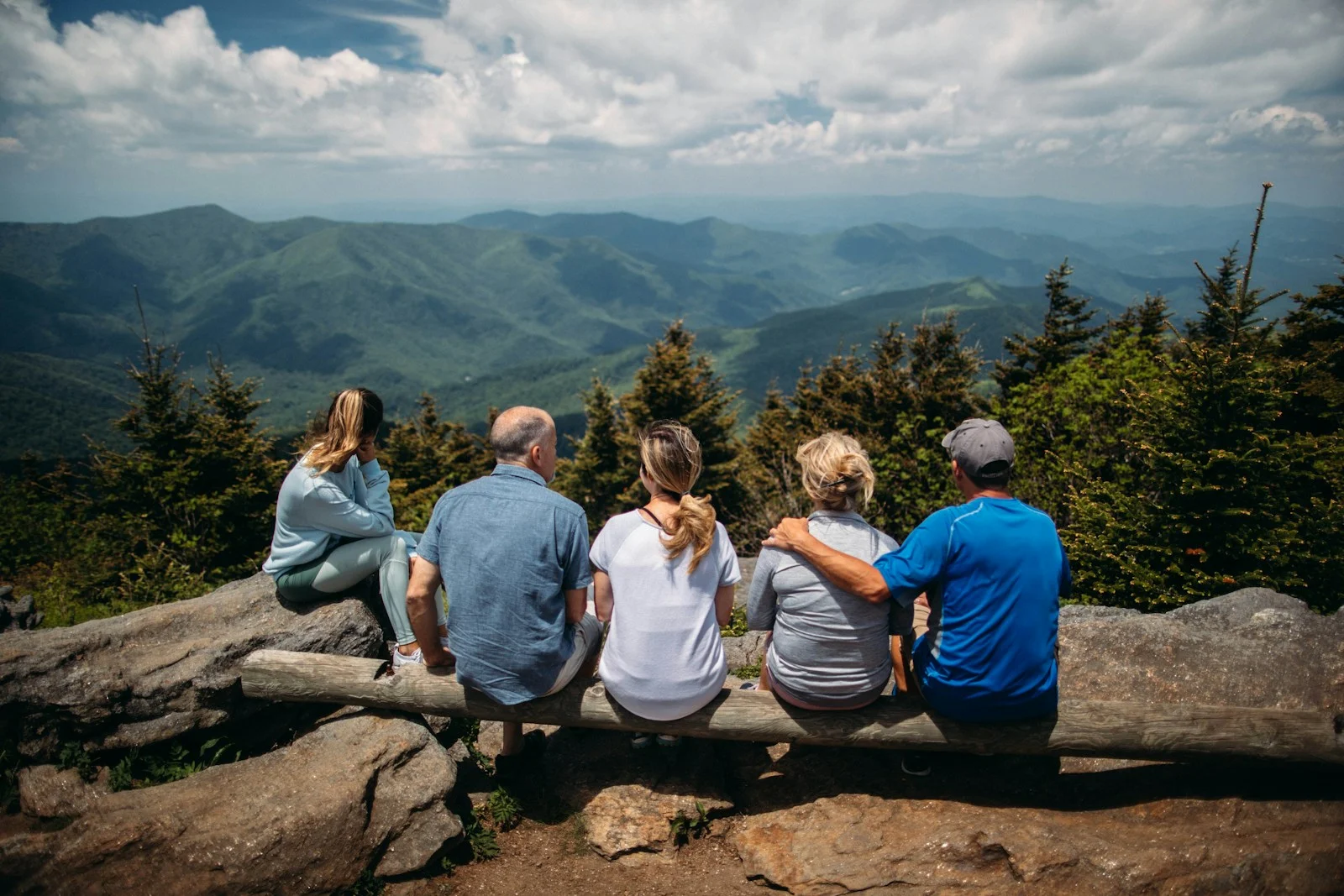 Family group of people sitting on rocks overlooking mountain