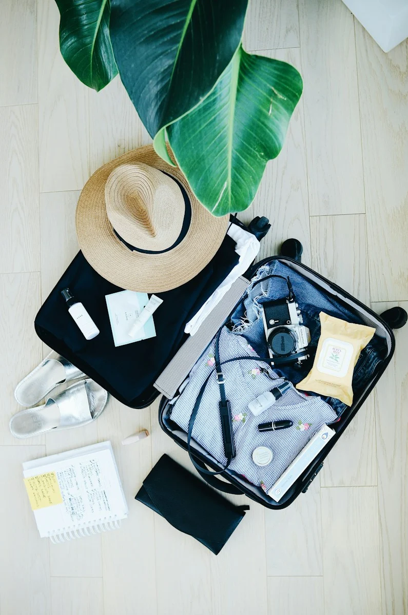 Expatrie : open suitcase with travel essentials and hat