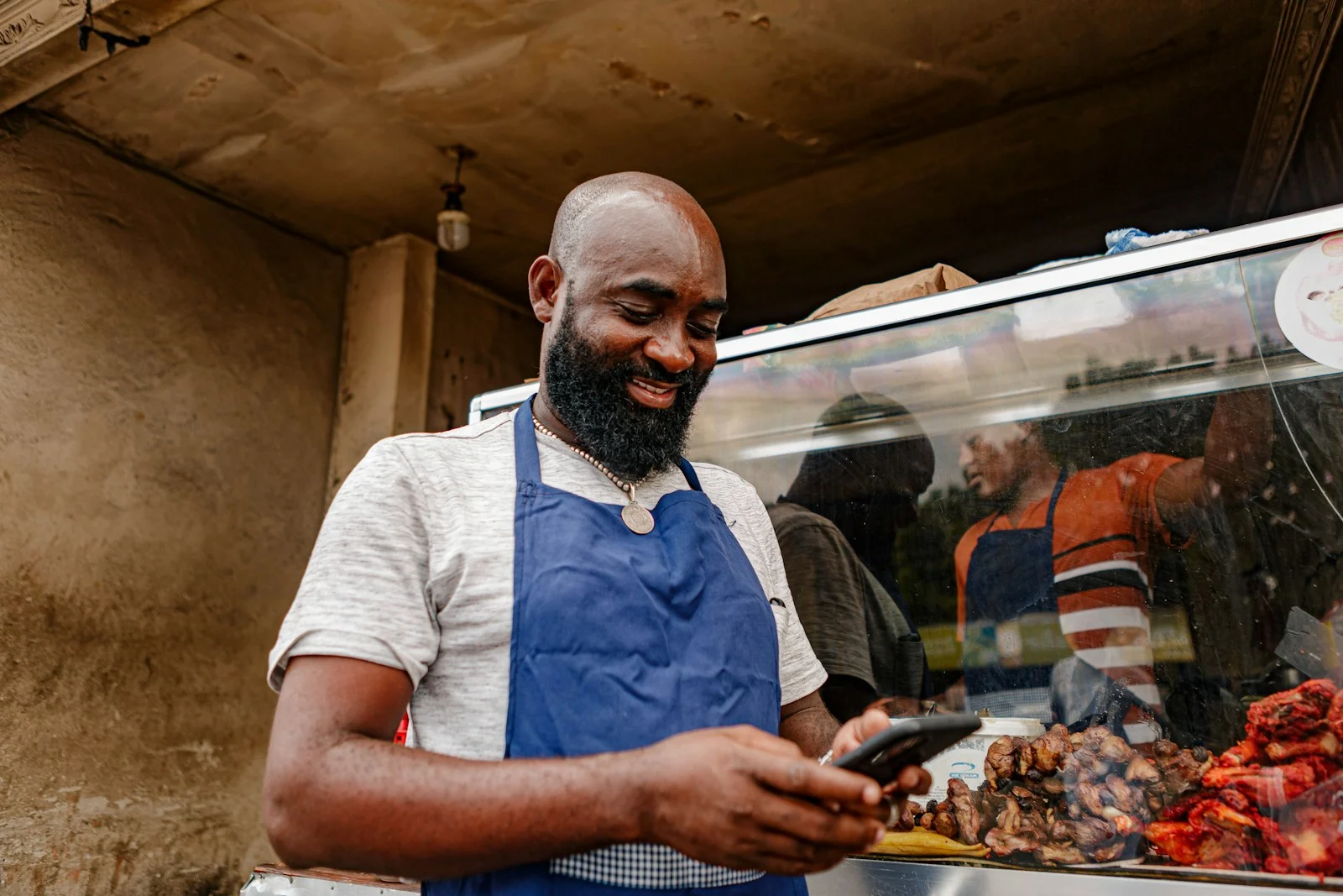 Un homme en tablier consultant son téléphone portable, illustration complémentaire santé micro-entrepreneur remboursement